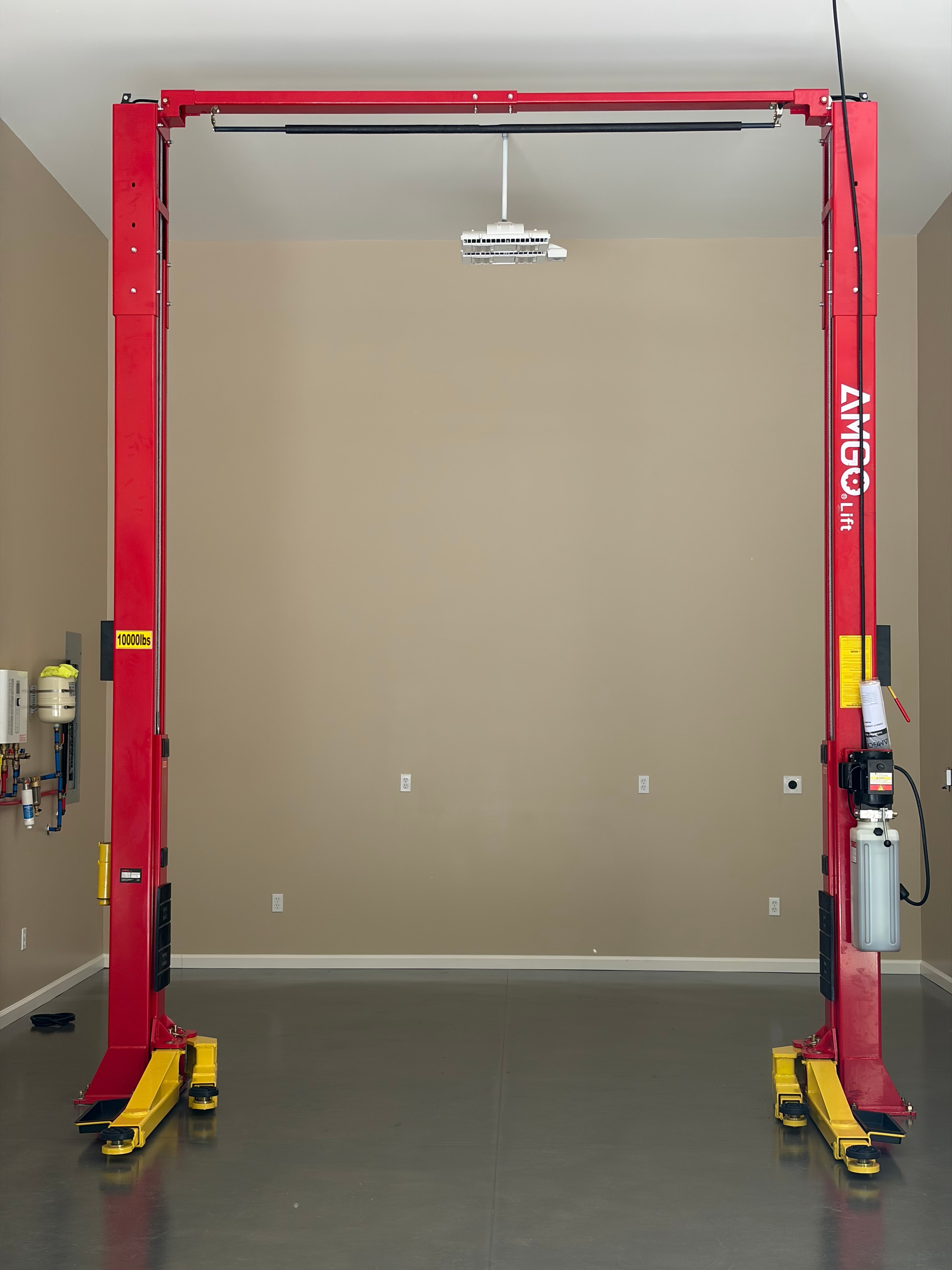 Red AMGO two-post lift overhead view, fresh install in a clean garage