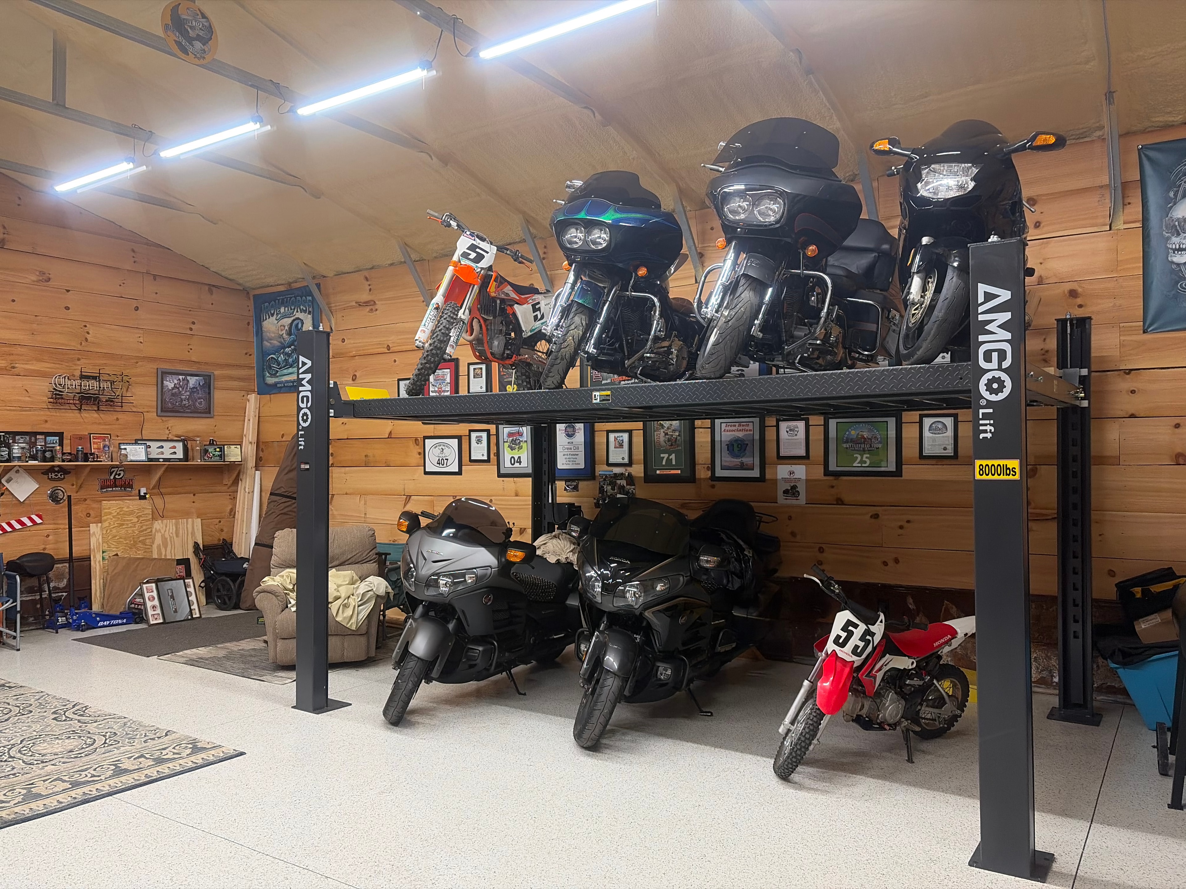 AMGO 4-post lift loaded with motorcycles in a wood-paneled garage