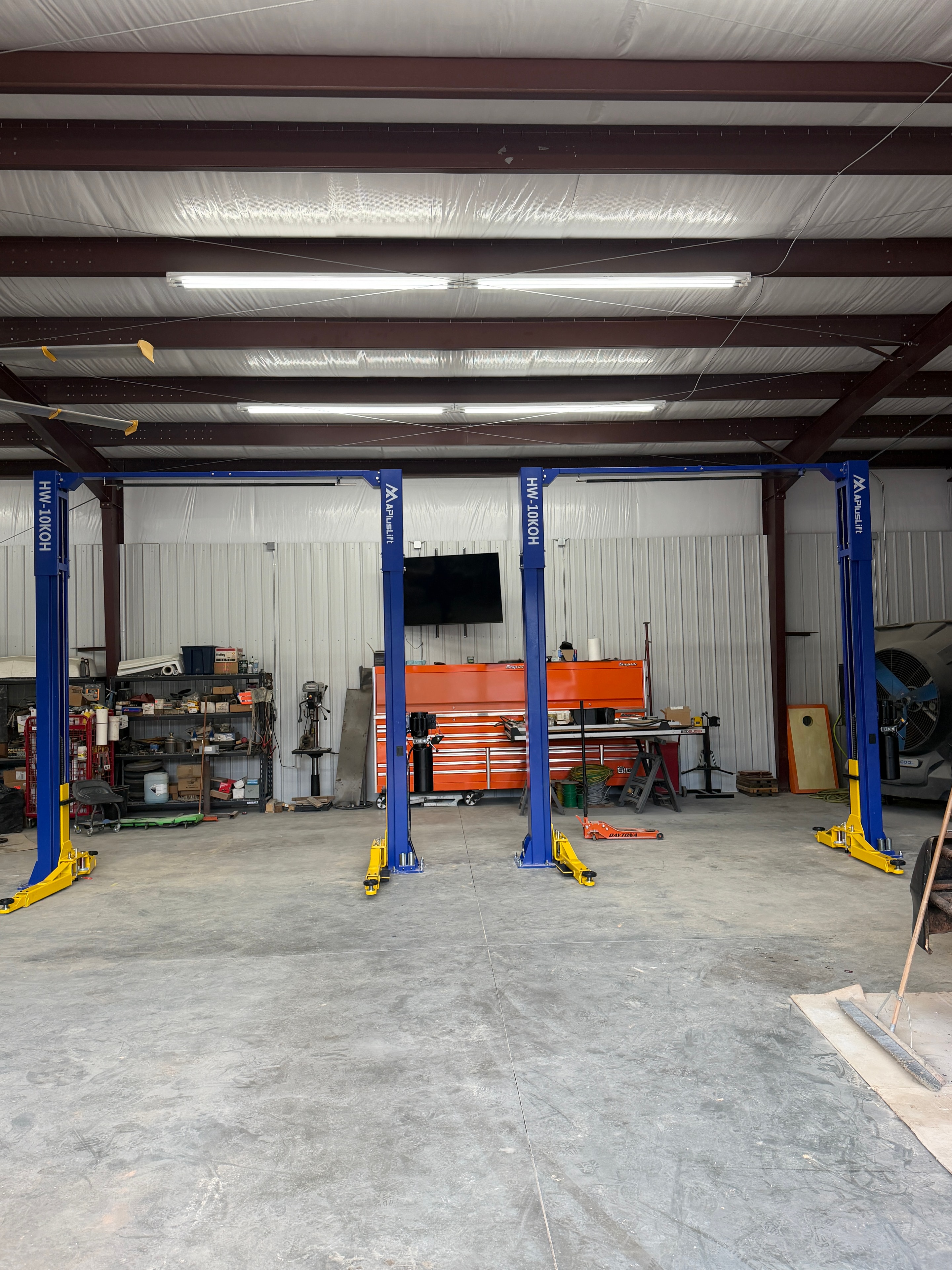 Two APlusLift HW-10KOH two-post lifts installed side by side in a commercial shop