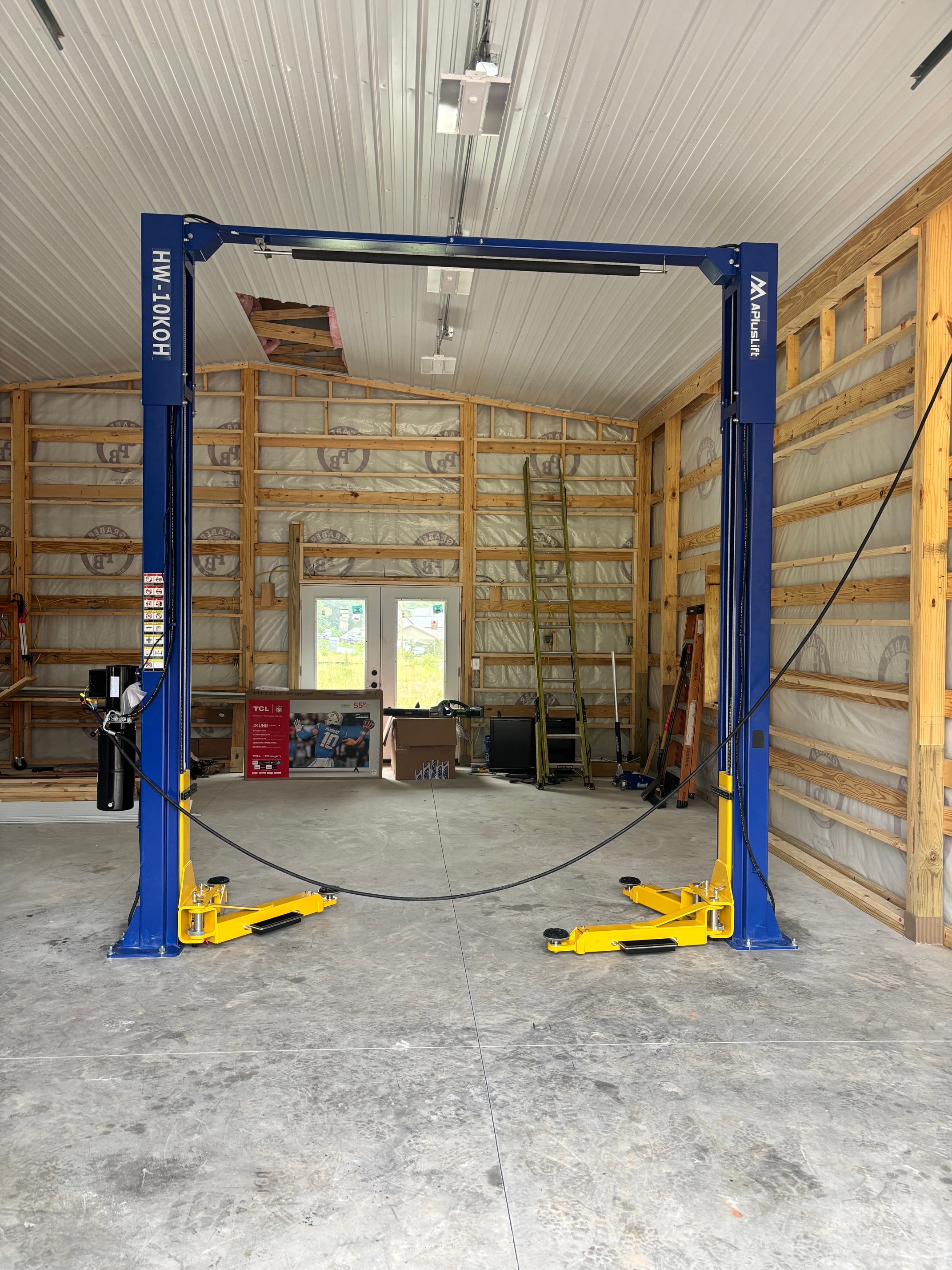 APlusLift HW-10KOH two-post lift freshly installed in a new build garage